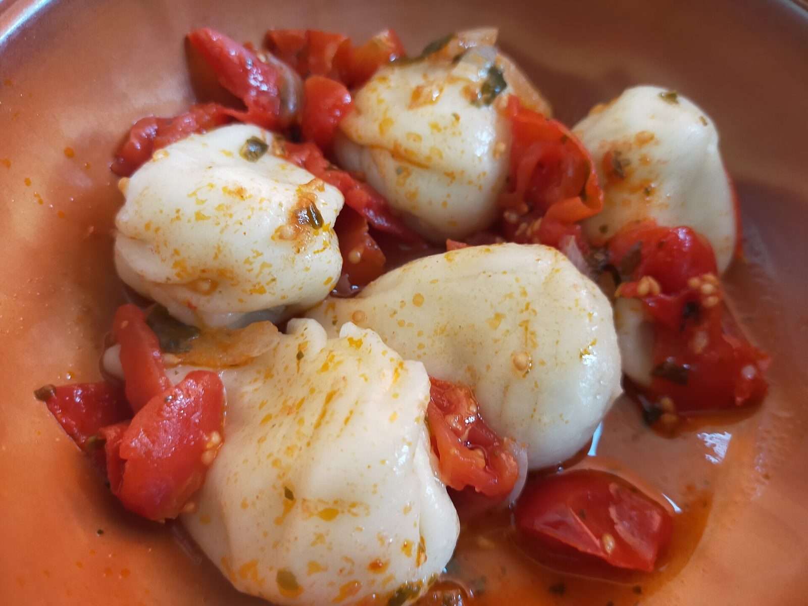 Culurgiones, pasta ripiena sarda con chiusura a spiga, serviti con pomodorini